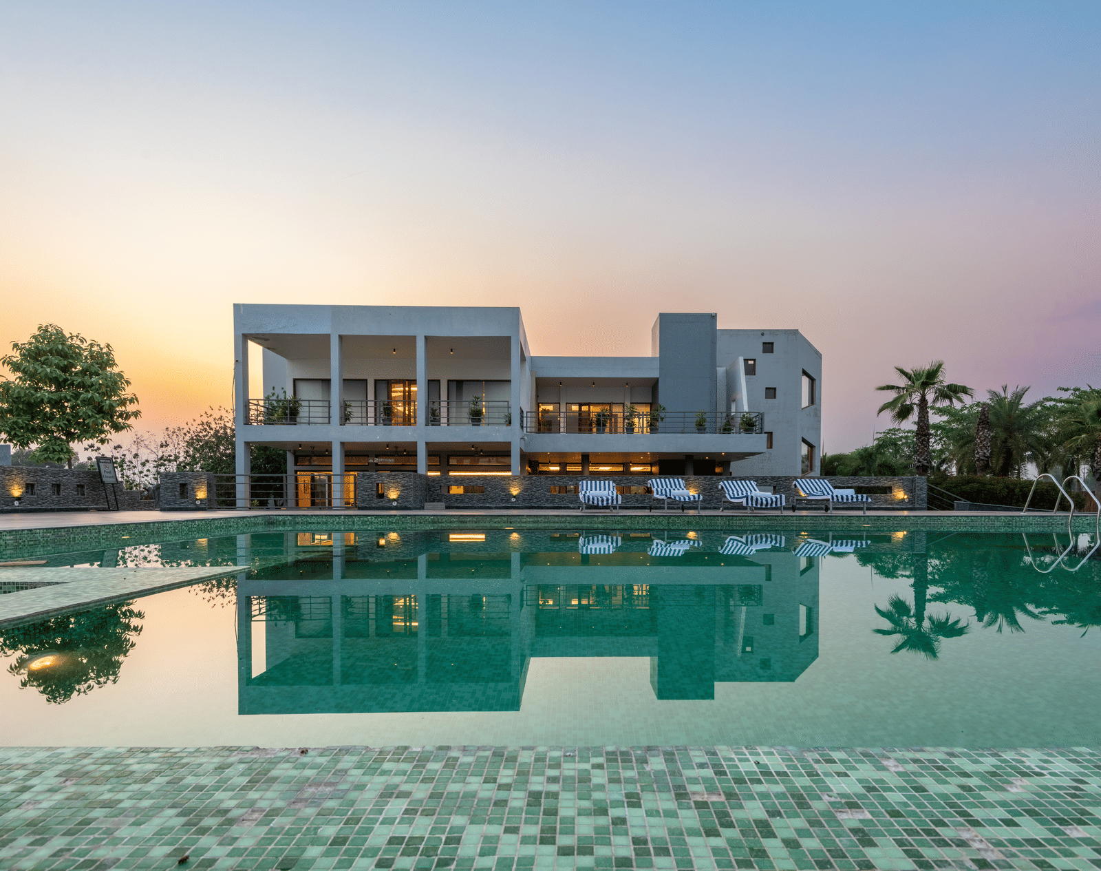 Facade view of DLS Forest Vines Resort with its reflection shimmering on the swimming pool under a clear sky.