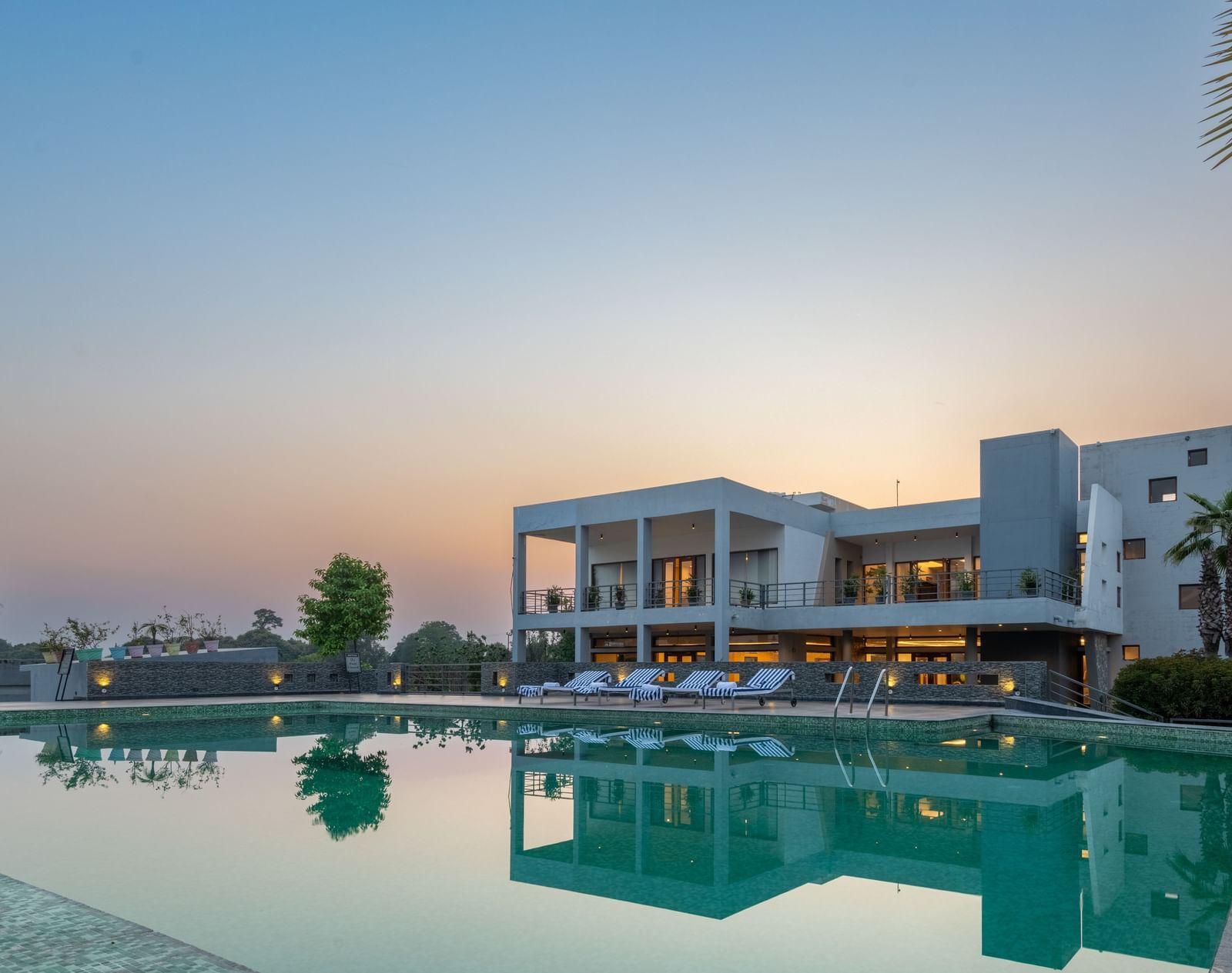 Facade view of DLS Forest Vines Resort with its reflection shimmering on the swimming pool under a clear sky.