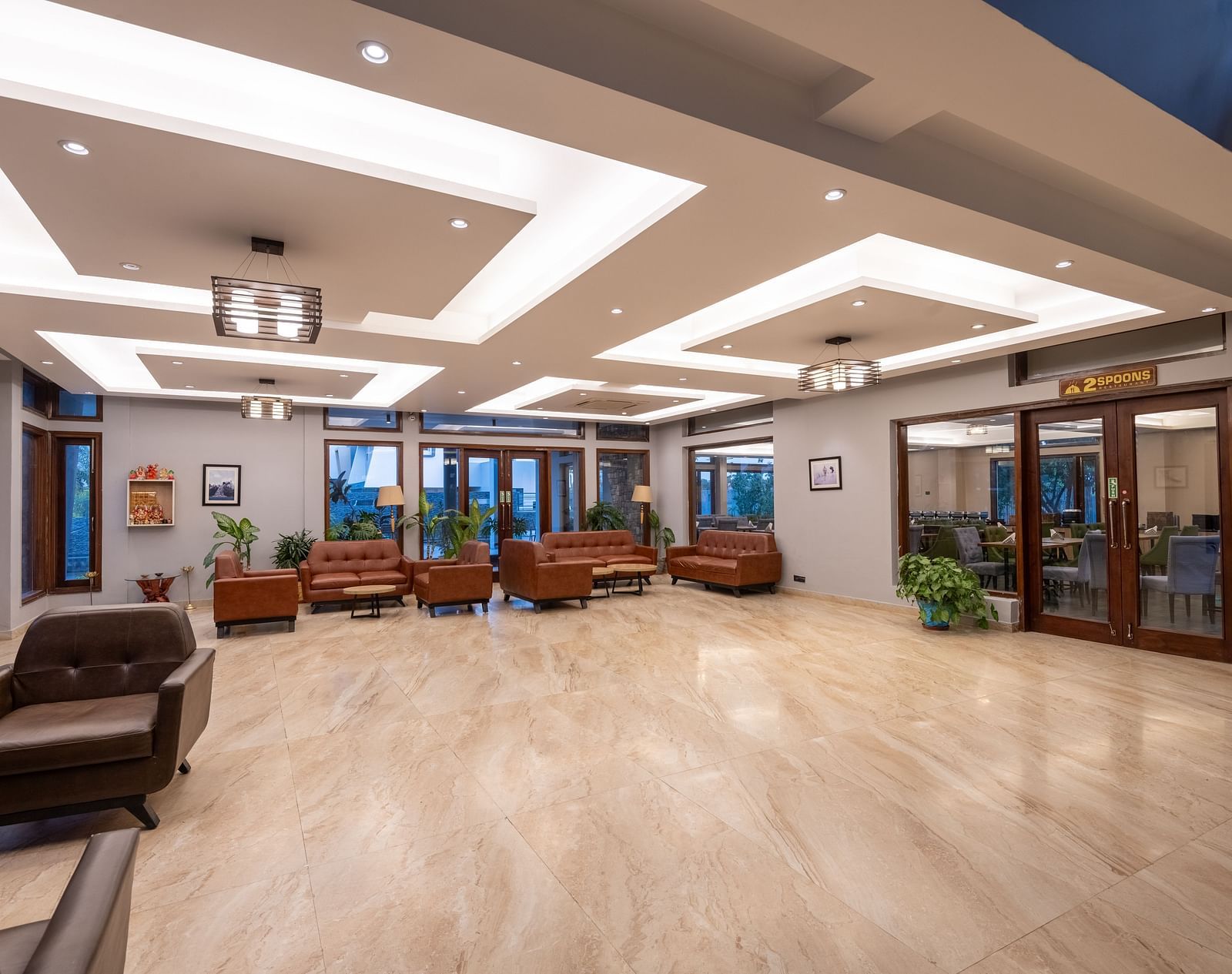 Reception area at DLS Forest Vines Resort, seen from the far end, featuring bright lighting and clean, cushioned sofas.