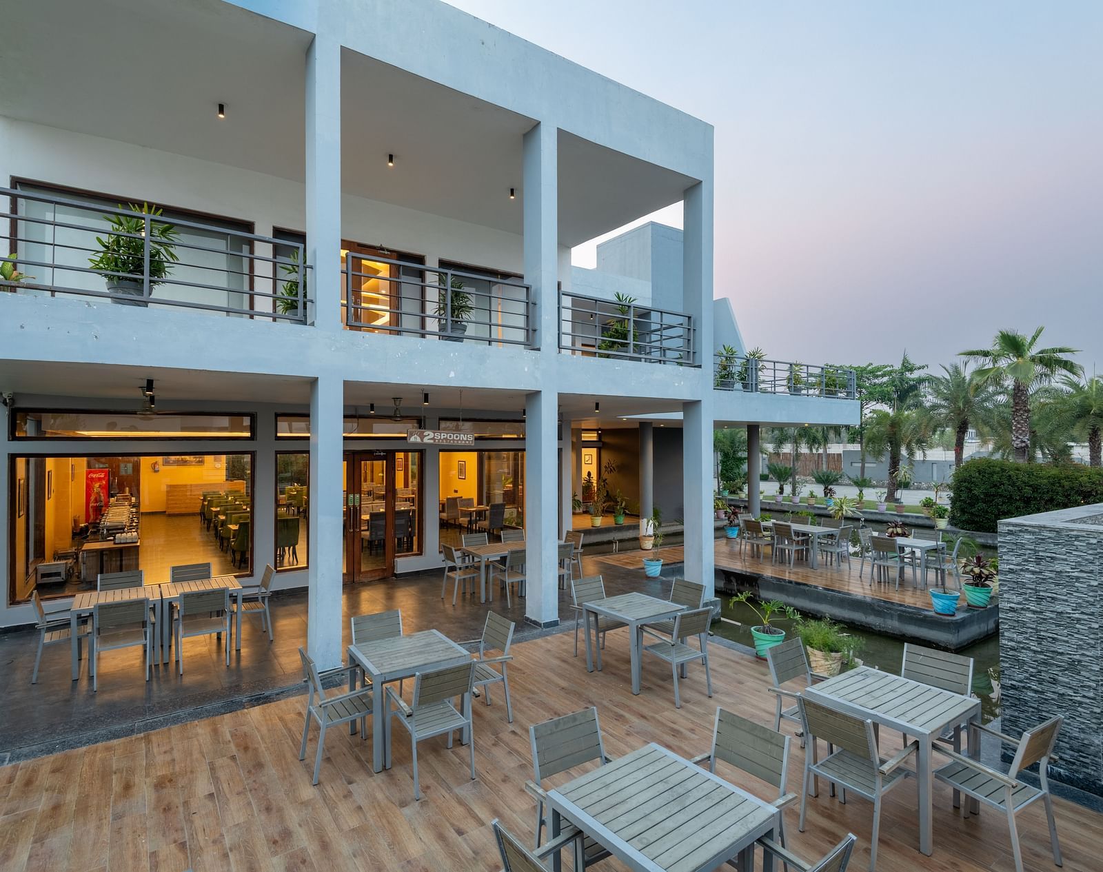 The facade of DLS Forest Vines Resort, glowing with warm light spilling from the windows and doors.