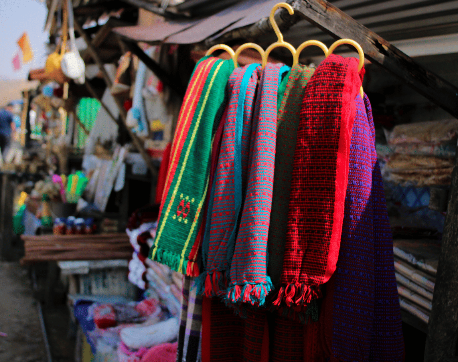 A close up of a wool muffler hung on a street shop with other things also in view.