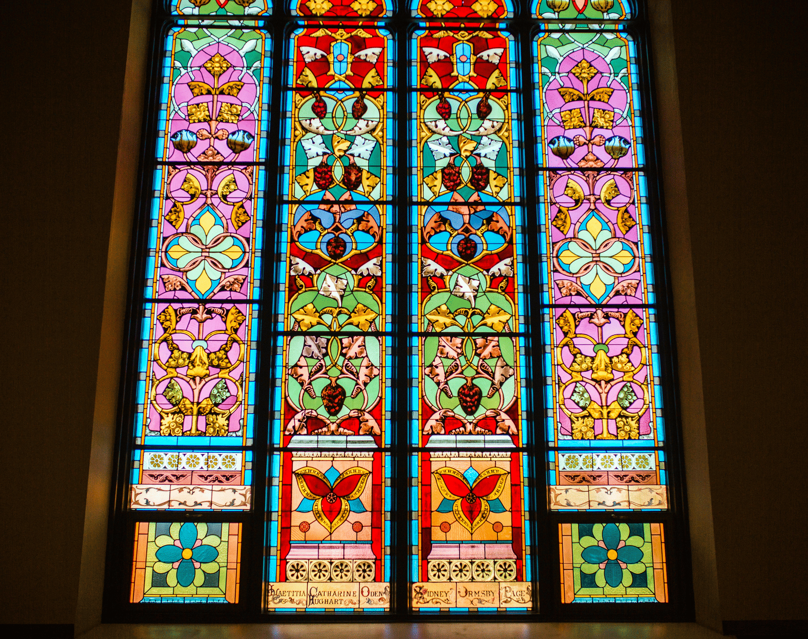 A close up of a stained glass inside a church with many colours seen on the glass.