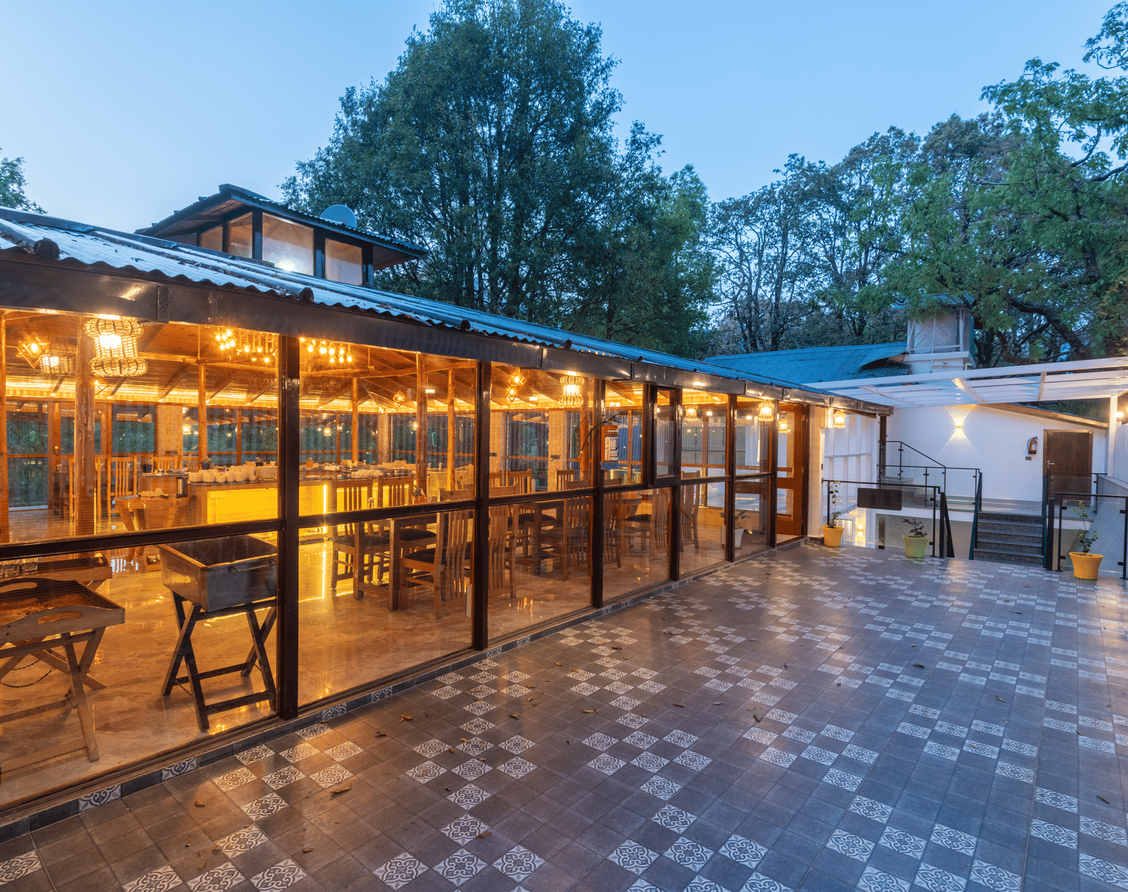A shot of the restaurant taken from outside featuring the outdoor seating area and trees in the background - DLS The Emerald, Nainital