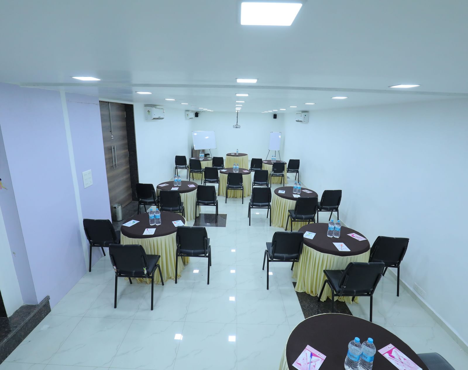 Round tables covered with table cloth, with chairs, water bottles, additional stationary, in the Regency banquet hall of Highland Resort.
