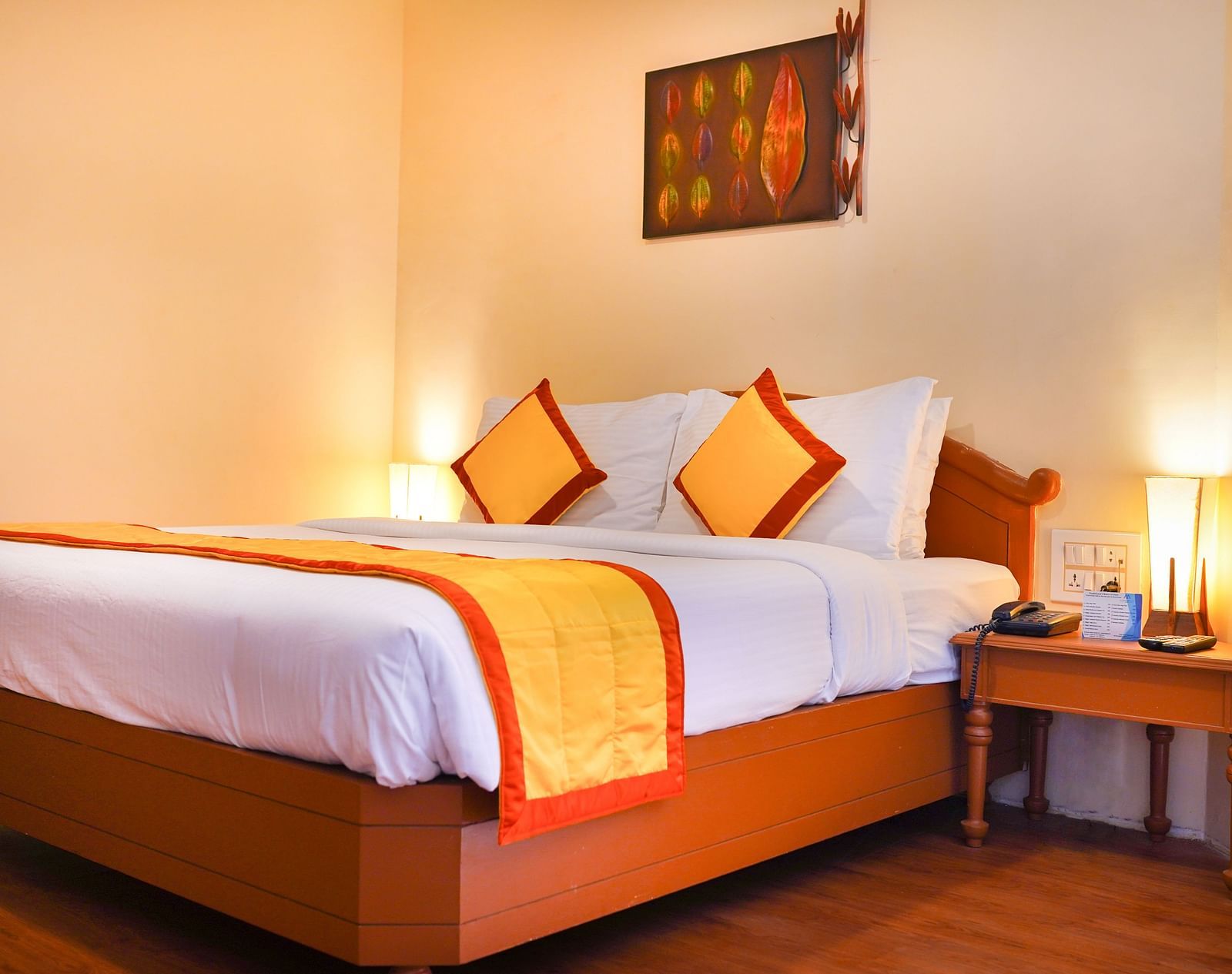 a view of a plush bed with yellow and orange cover and pillows at La Montana By TGI, Ooty