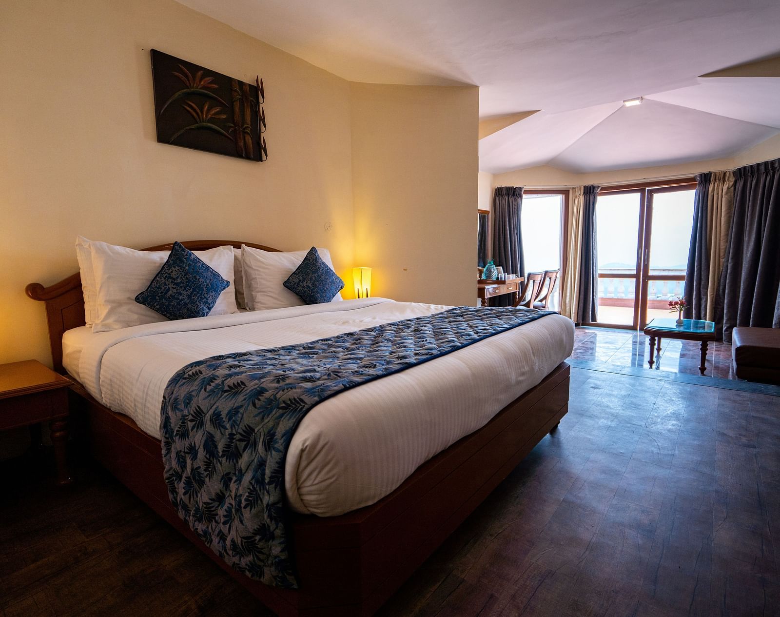comfy bed with blue duvet and pillows at La Montana By TGI, Ooty