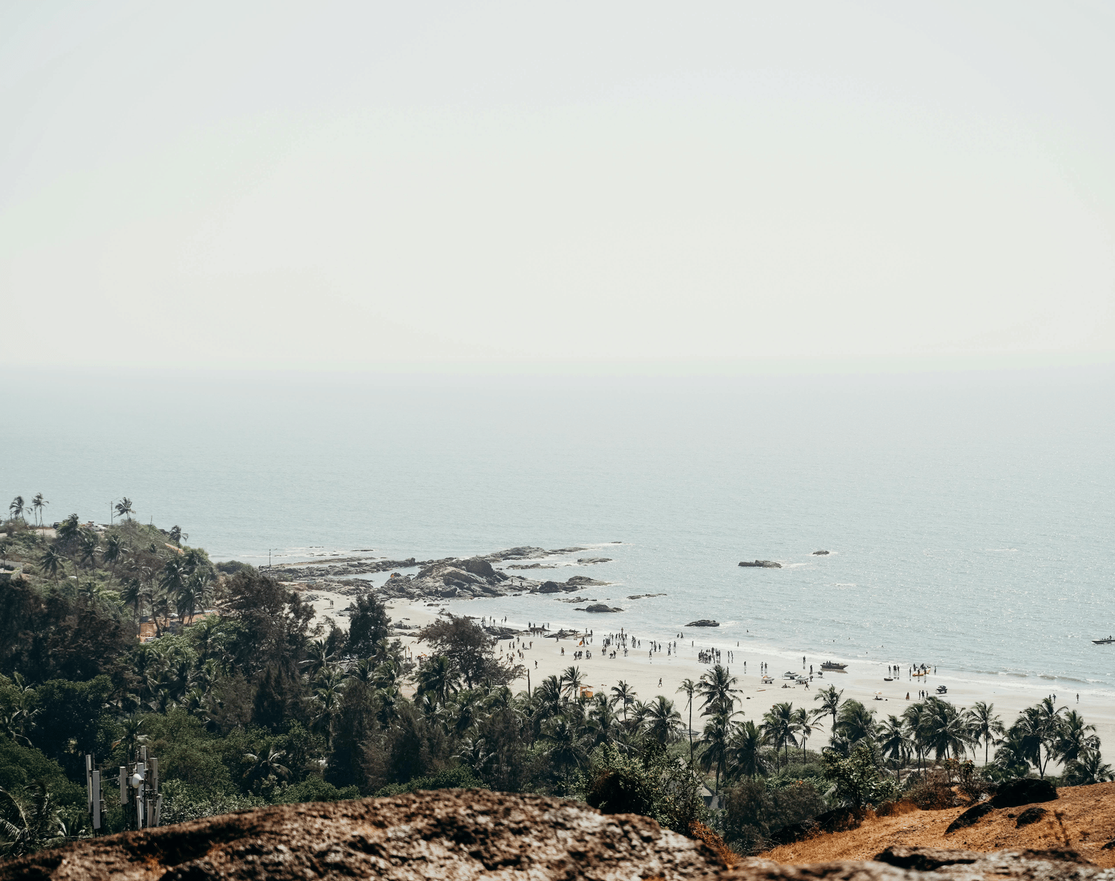 A serene coastal view with cliffs, trees, and boats scattered across the calm sea.
