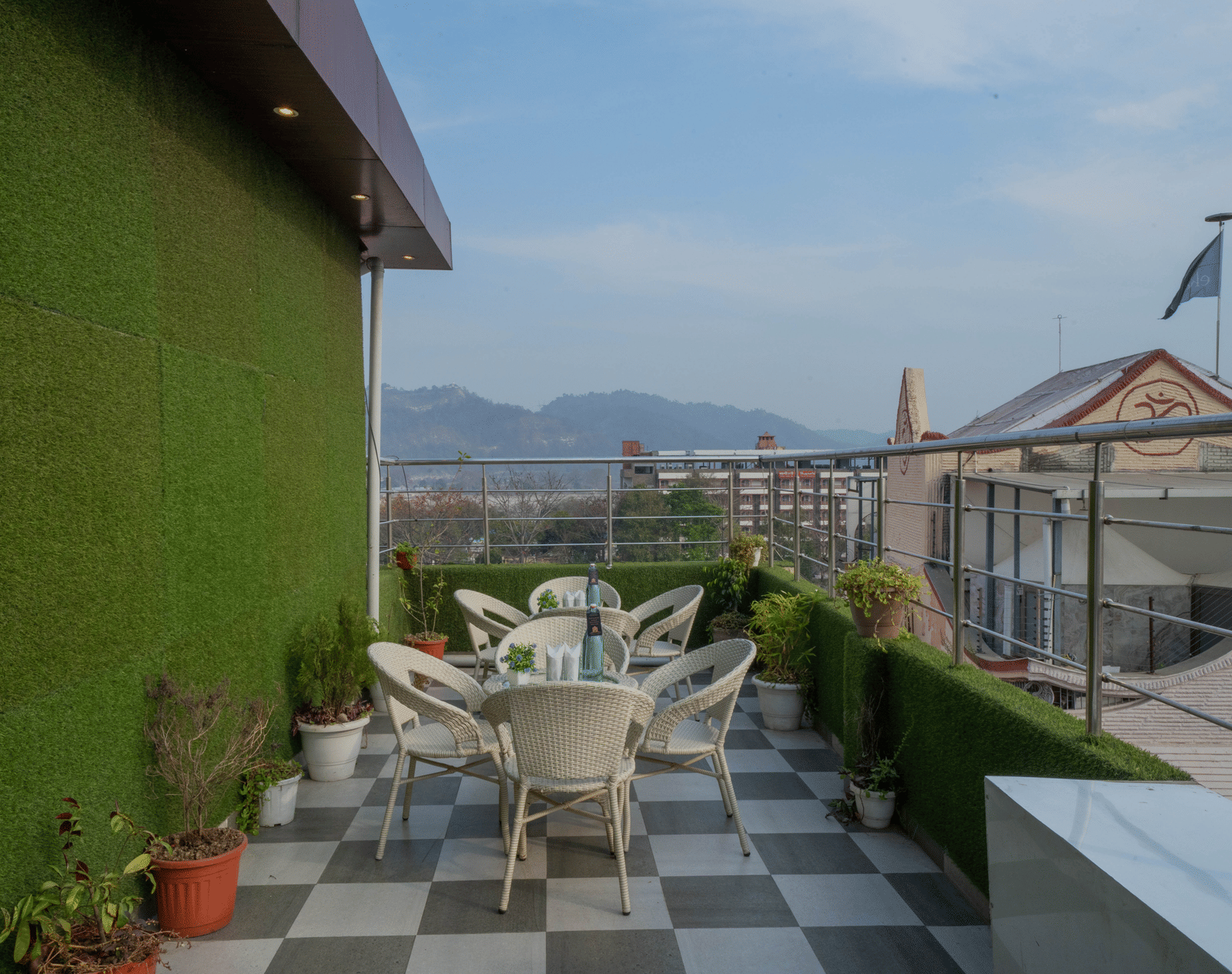 Rooftop terrace seating area with tables and chairs and a view of the surrounding hills - Perfectstayz Premium at Har Ki Pauri Road (Ganga Heights)