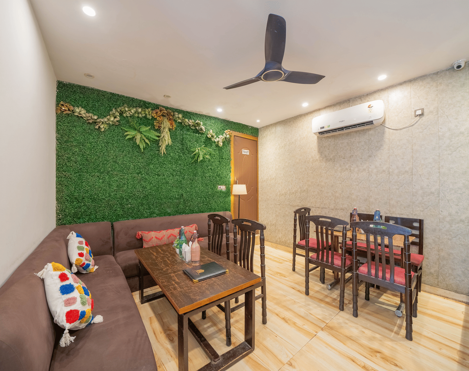Lounge or dining area inside with a ceiling fan, tables, and chairs, featuring a green wall accent - Perfectstayz Premium at Har Ki Pauri Road (Ganga Heights)