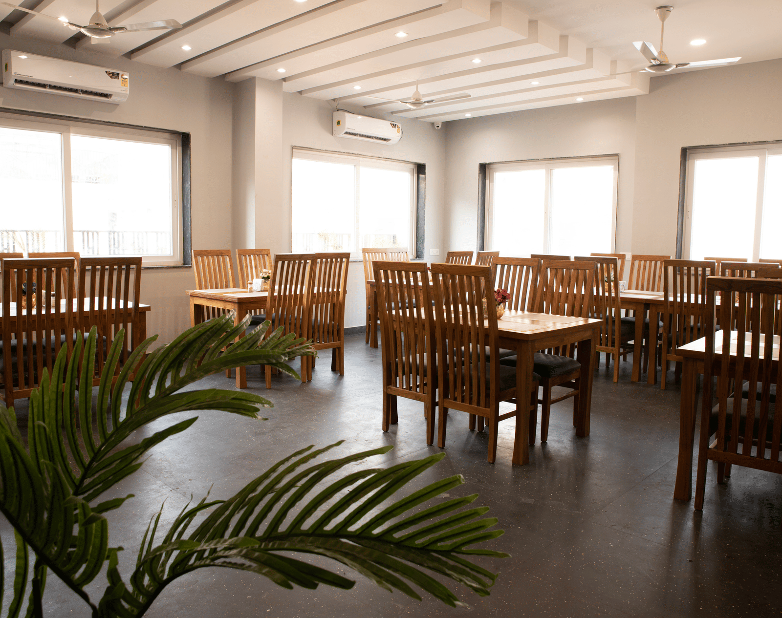 A dining area with tables, chairs, and a potted plant at Perfectstayz Premium Laxmi Heritage.