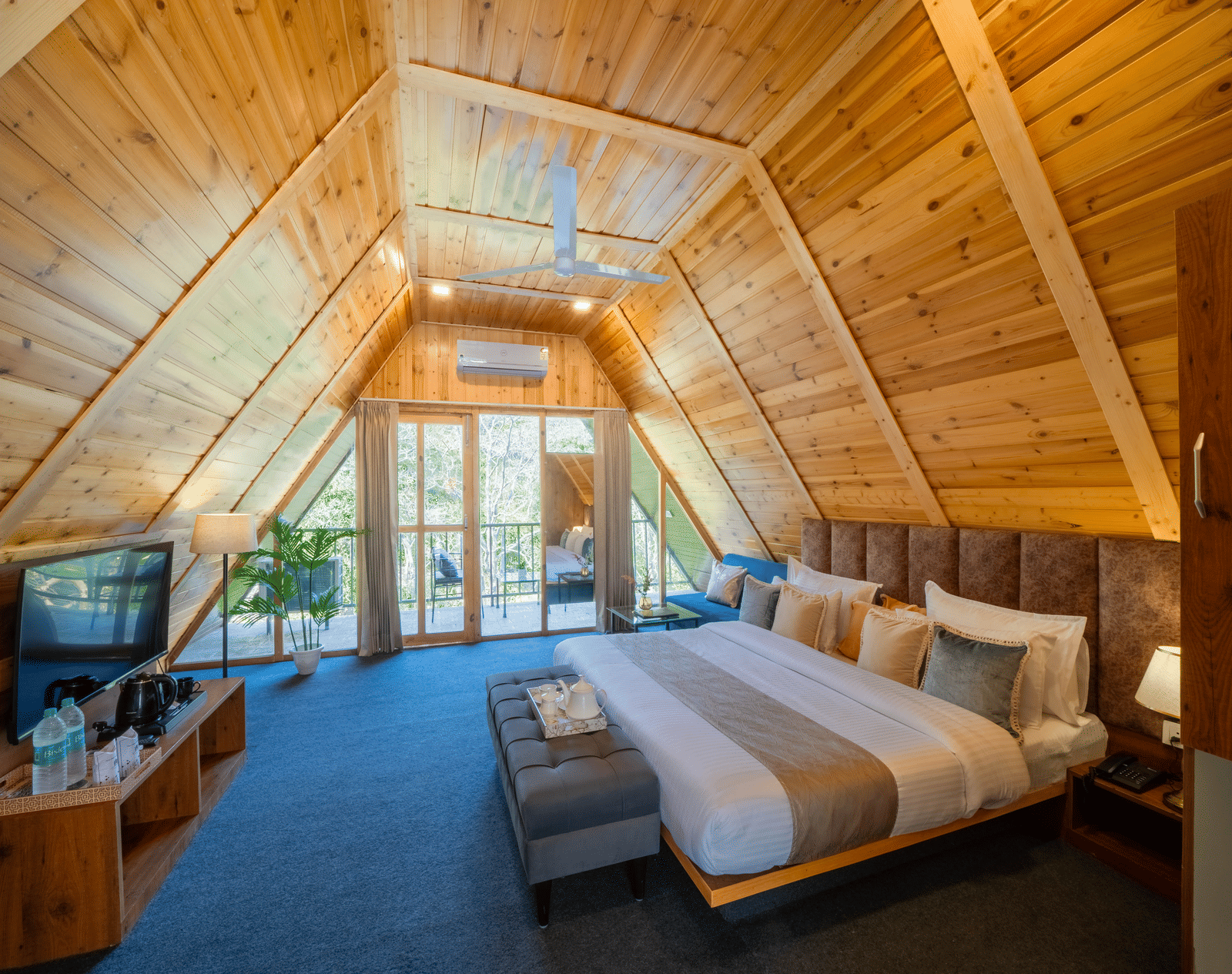 The A-frame bedroom at Perfect Stayz The Jungle Resort contains a bed, a television, and a wooden ceiling.