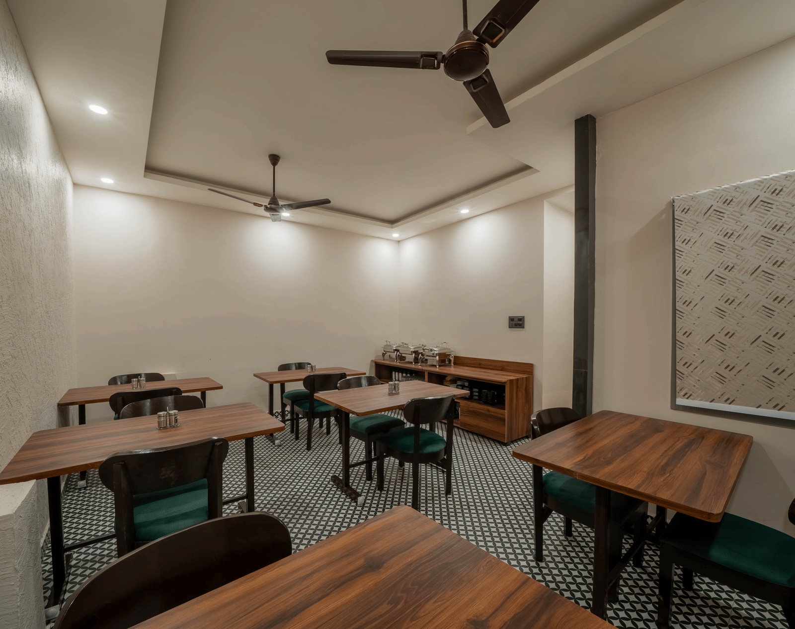 Side view of a dining room with dark wooden tables, chairs, and ceiling fans - Perfectstayz Value Aalaya Suites, Haridwar