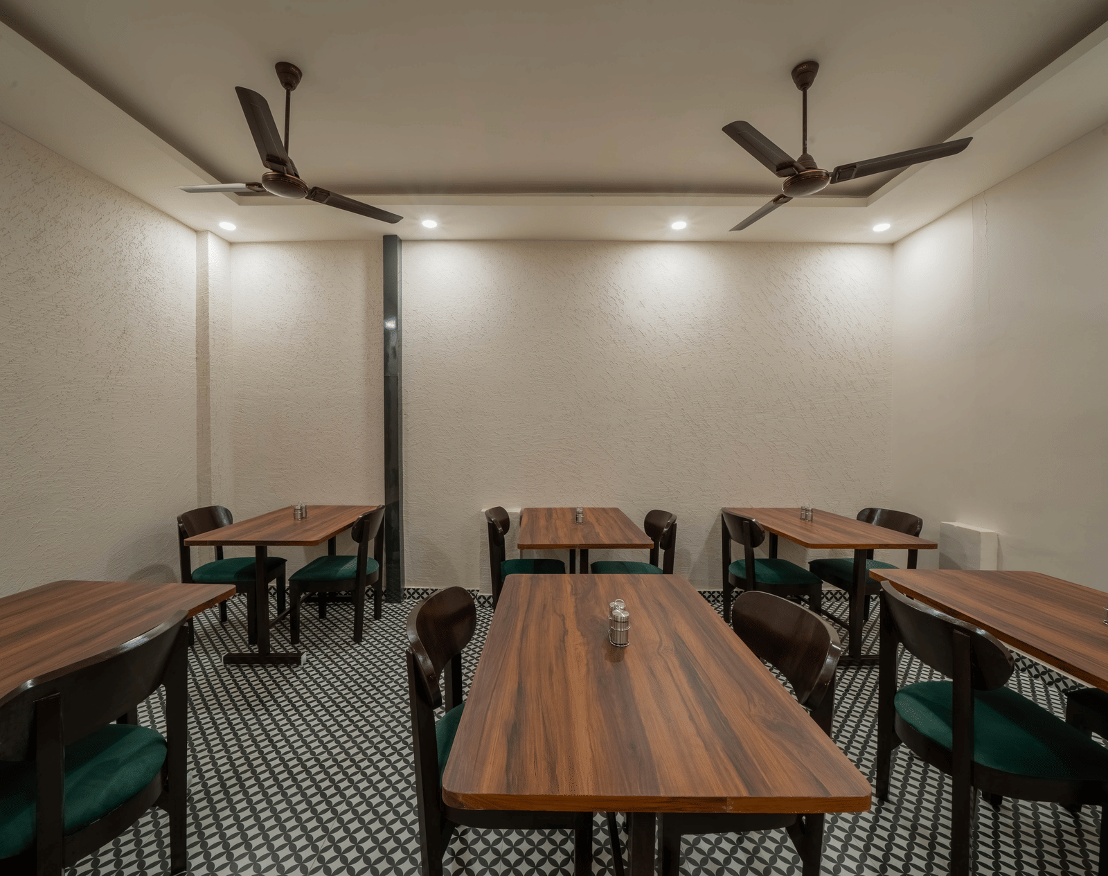 Spacious dining area with multiple dark wooden tables and chairs, a simple white ceiling with a fan, and bright lighting - Perfectstayz Value Aalaya Suites, Haridwar