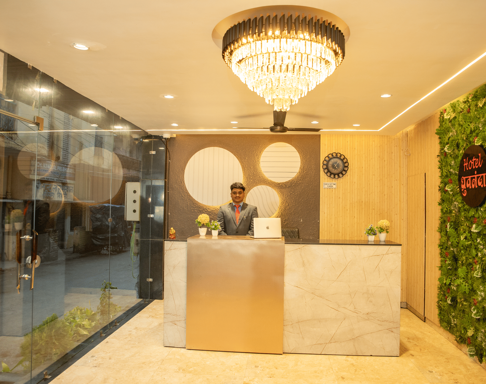 A staff member dressed in business formals standing behind the reception desk at Perfectstayz Value Dhruv Nanda.