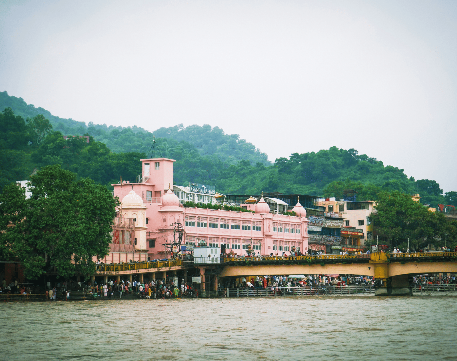  Exterior view of a river, bridge, and colourful buildings on the bank of ganges.