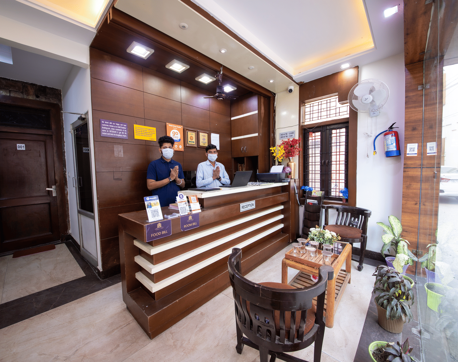 Hotel reception area featuring a modern wooden desk, staff behind the counter, and a small seating area - Perfectstayz Value Grey Castle, Haridwar