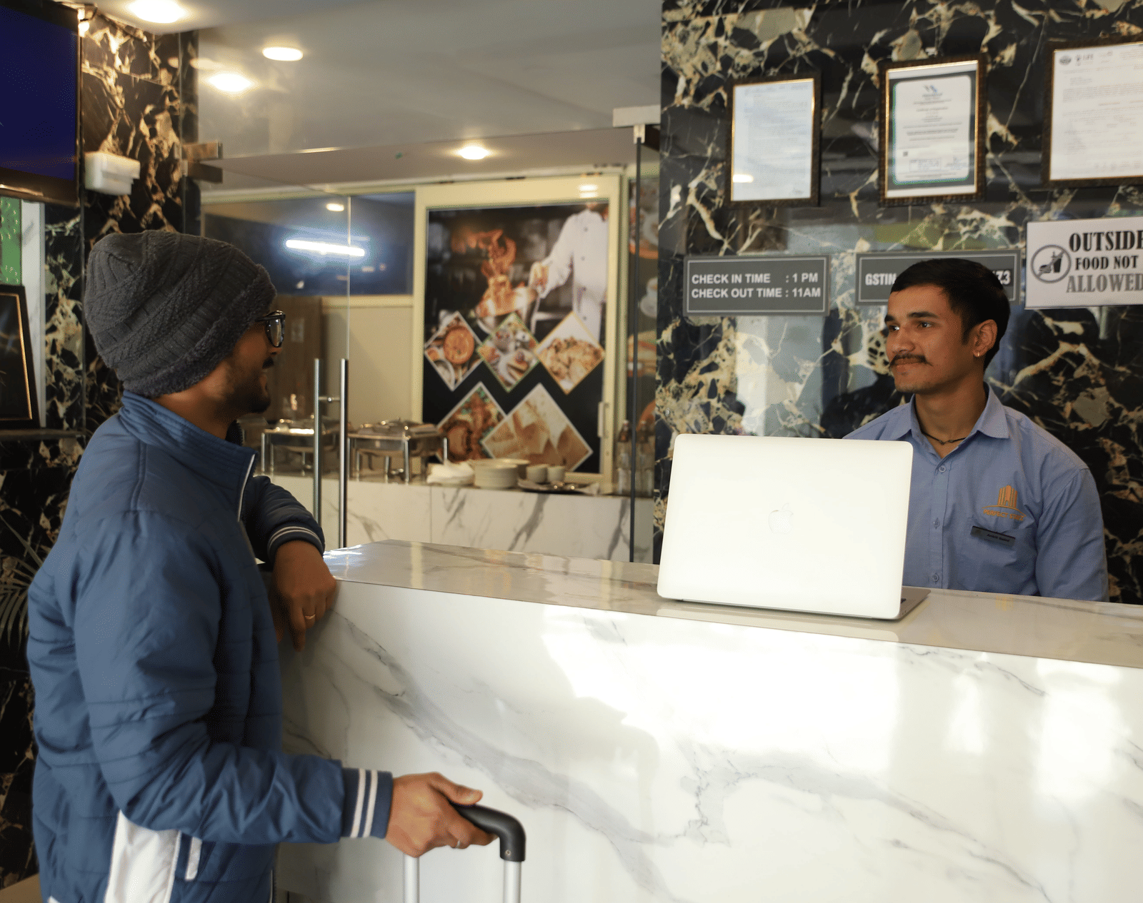 A man wearing a turban speaking to a staff member behind a reception counter with a laptop | Perfectstayz Value Hills