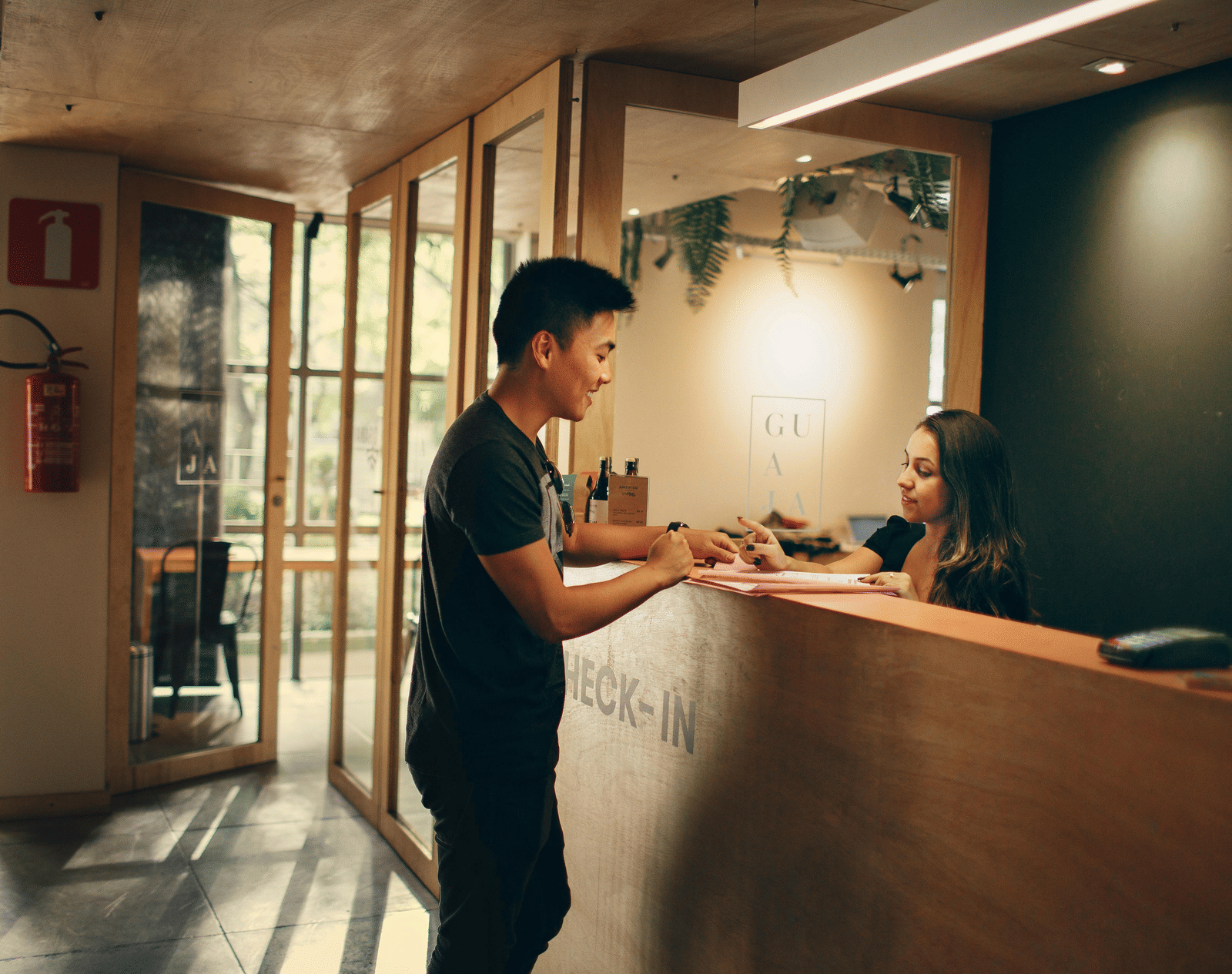 A hotel guest checking in at a wooden reception with a clerk smiling.