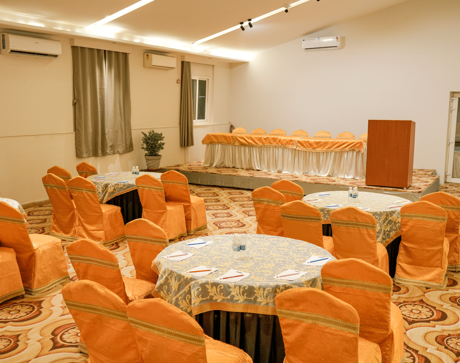 Banquet hall with round tables and chairs at Pravasa Hotel, Kolhapur.
