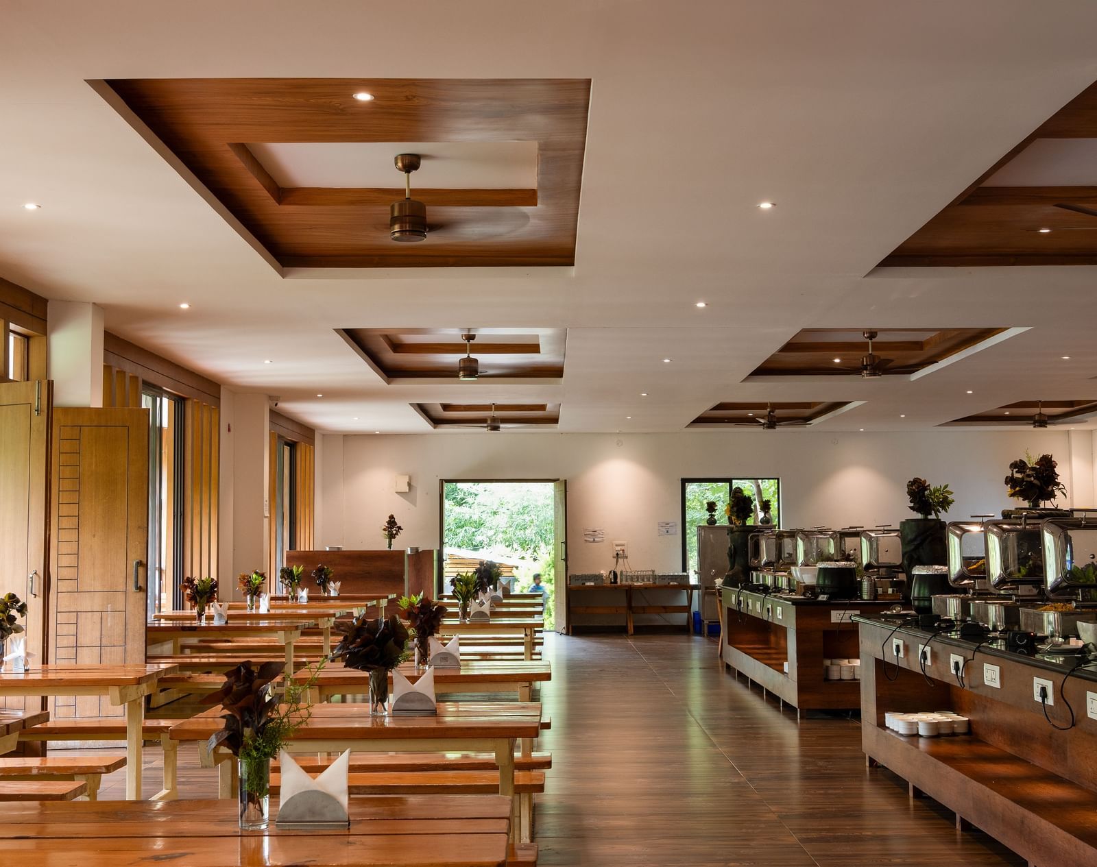 A well-lit restaurant interior features a buffet line on the left and dining tables with chairs on the right, all under a decorative wooden ceiling | Lake View Restaurant