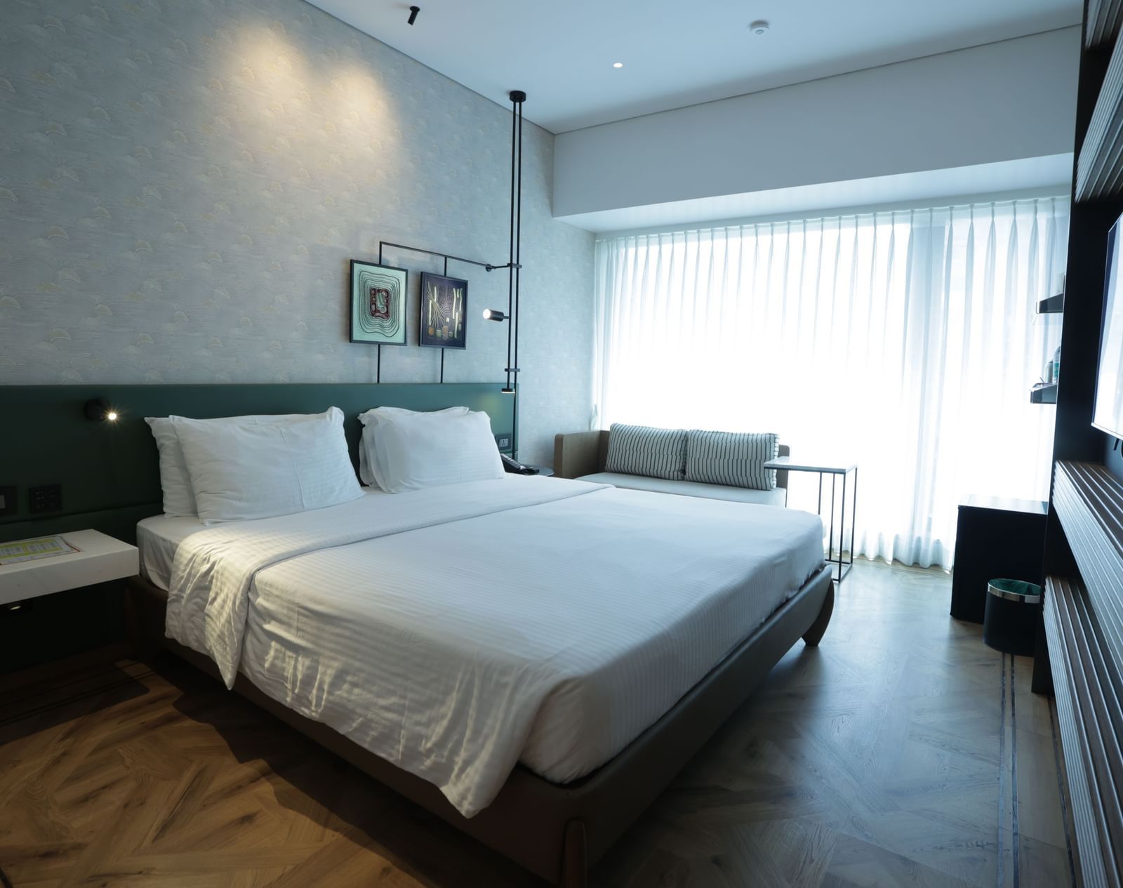 Well lit bedroom with a comfortable king bed, wall decor and curtained windows.