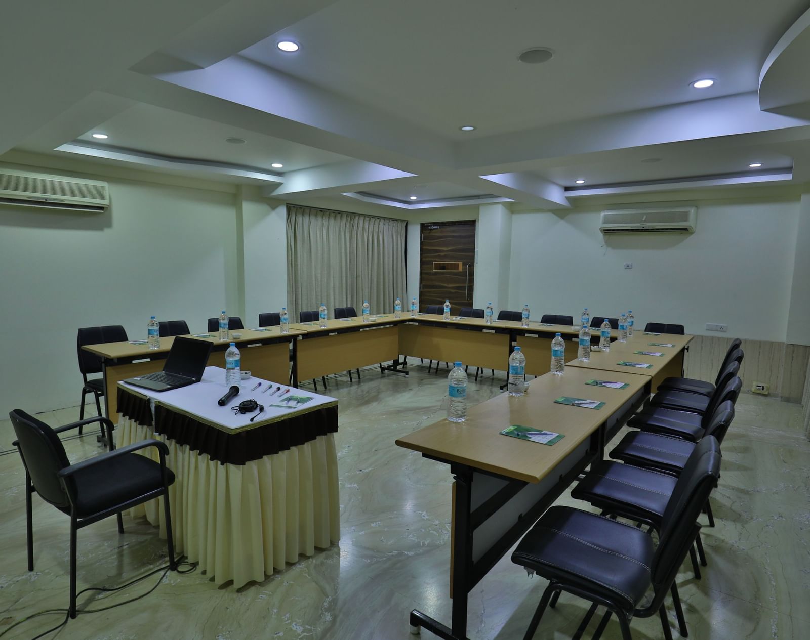 A formal meeting room with a large U-shaped table, office chairs, and a podium at the front - Retreat Heritage, Lonavala