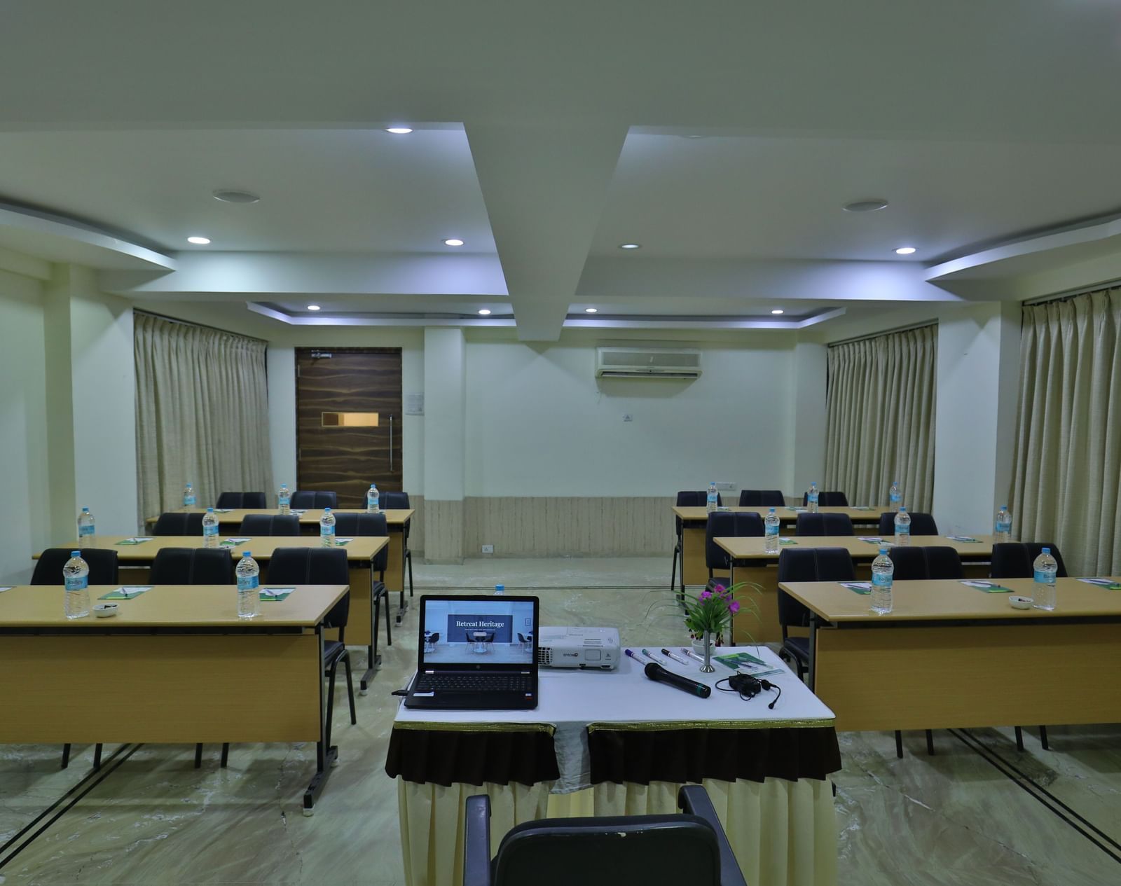 An event space setup with desks, chairs, and presentation equipment at the front - Retreat Heritage, Lonavala