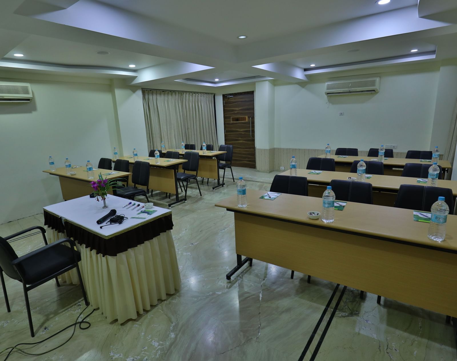 A conference room featuring multiple tables arranged individually, chairs, and a podium at the front - Retreat Heritage, Lonavala