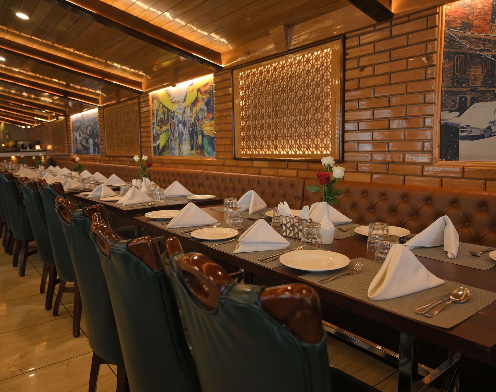 Tables and chairs arranged neatly with cutlery and decor ready for guests, with paintings on walls at Royal Comfort Regency