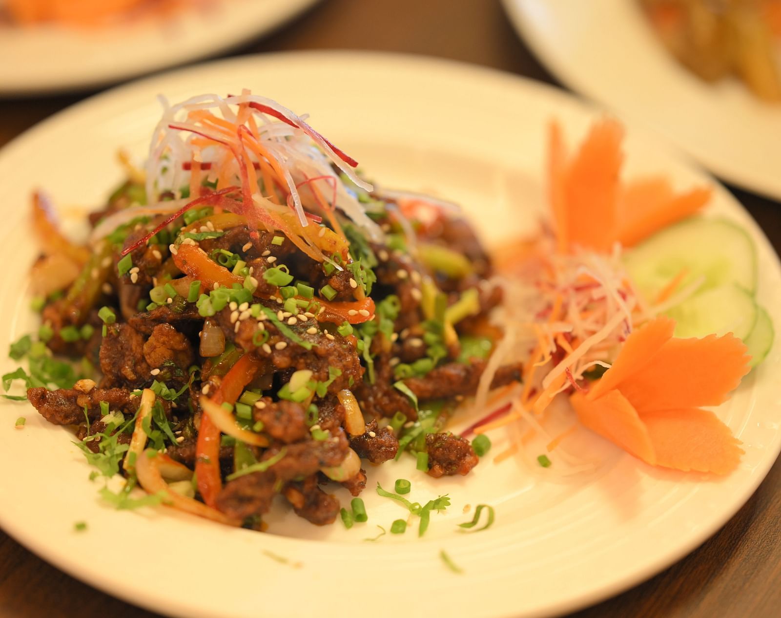 A plate of vibrant stir-fried meat with colorful vegetables and garnishes at Royal Comfort Regency.