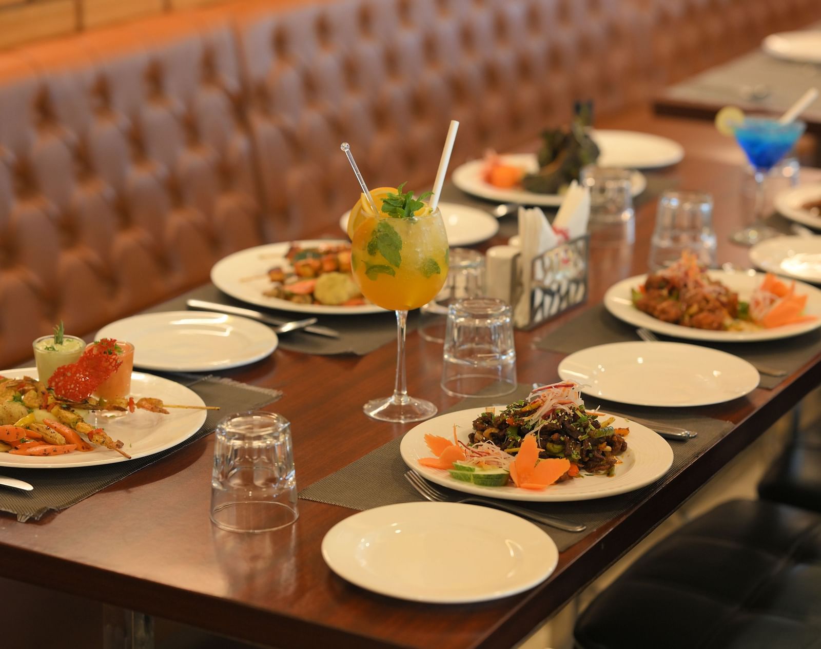 A dining table elegantly set with diverse, colourful dishes and refreshing drinks at Royal Comfort Regency.