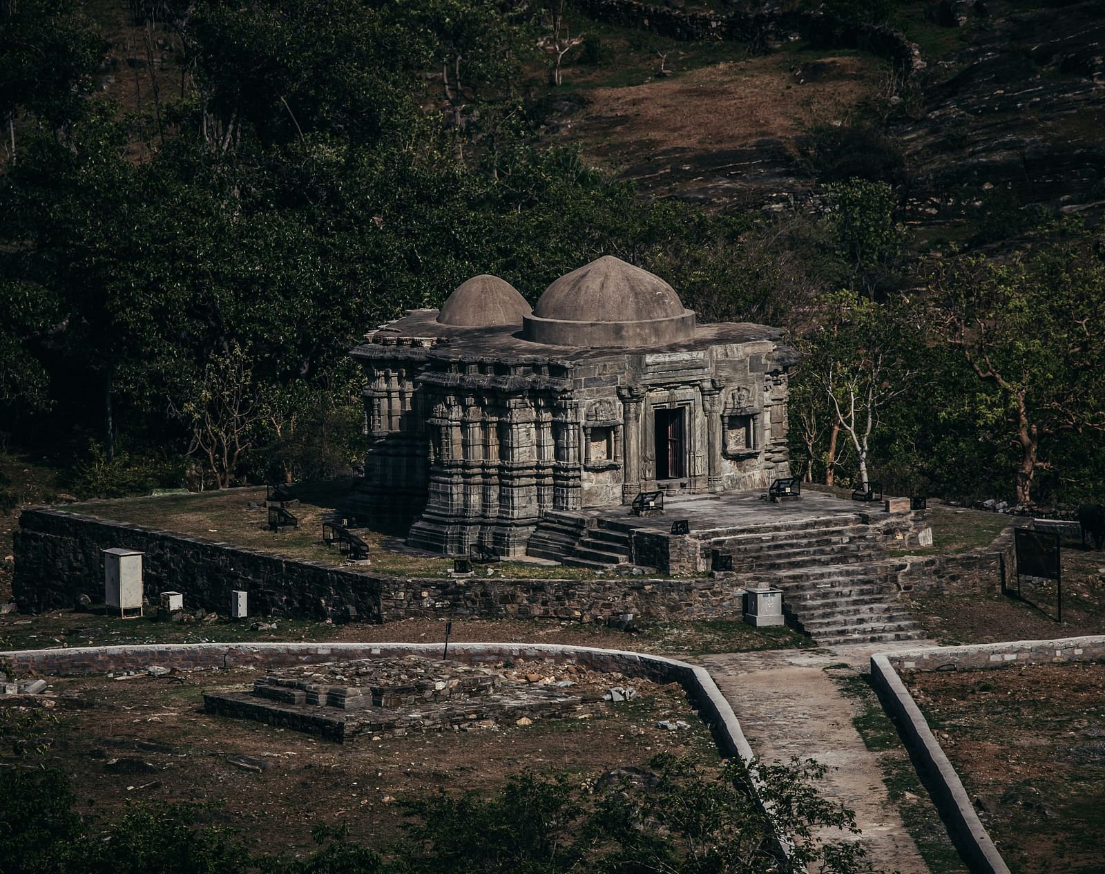 A far out view of a stone structure inside the Kumbhalgarh fort with steps leading to it.