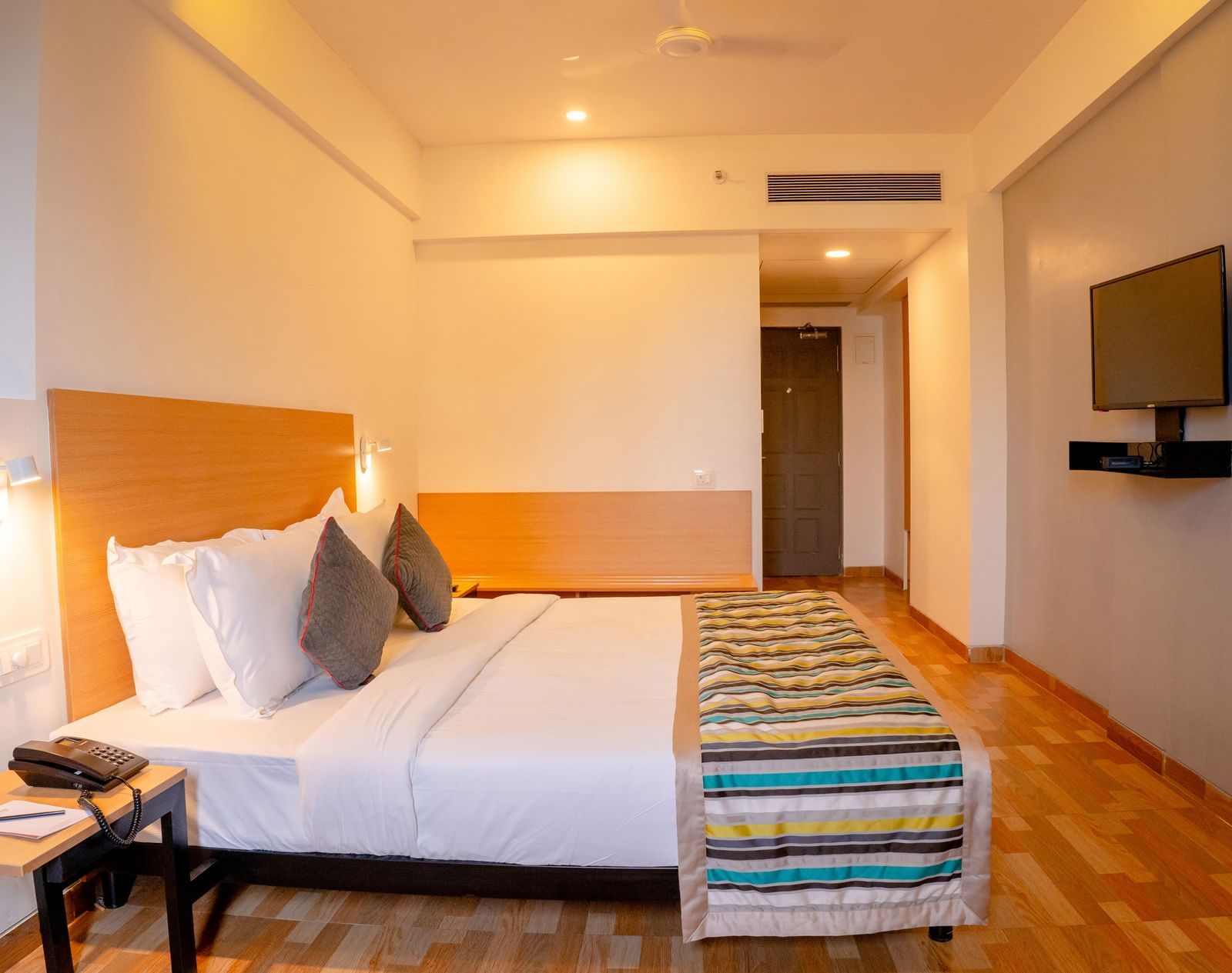 Bedroom at TGI Ameya Grand with a king bed and a side table.