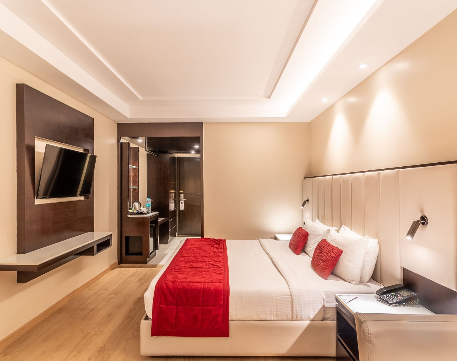 Bedroom with mounted TV, bedside lighting, and seating area- TGI Grand Fortuna, Krishnagiri Main Road, Hosur
