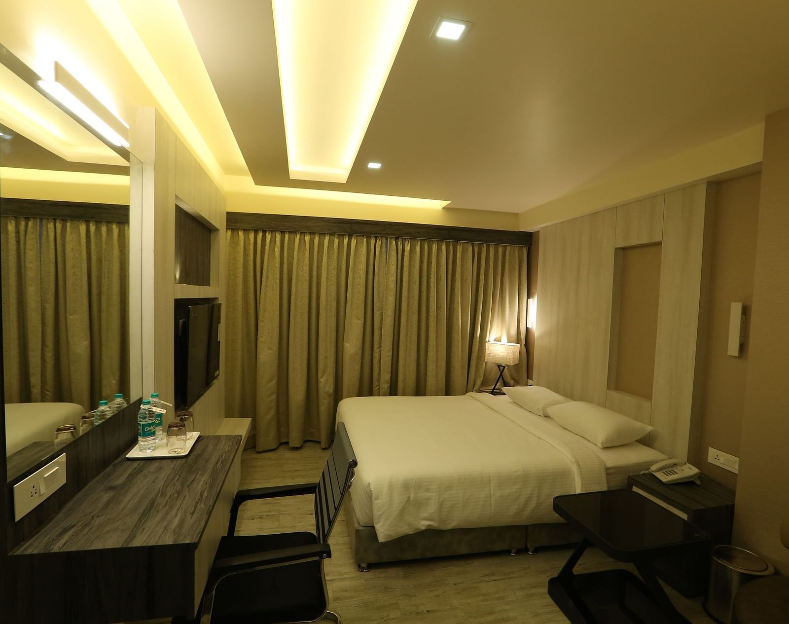 Premium Room featuring a king size bed, desk with a mirror, chair, and ambient lighting, showcasing the room's layout and decor - TGI SPS Grand, Coimbatore