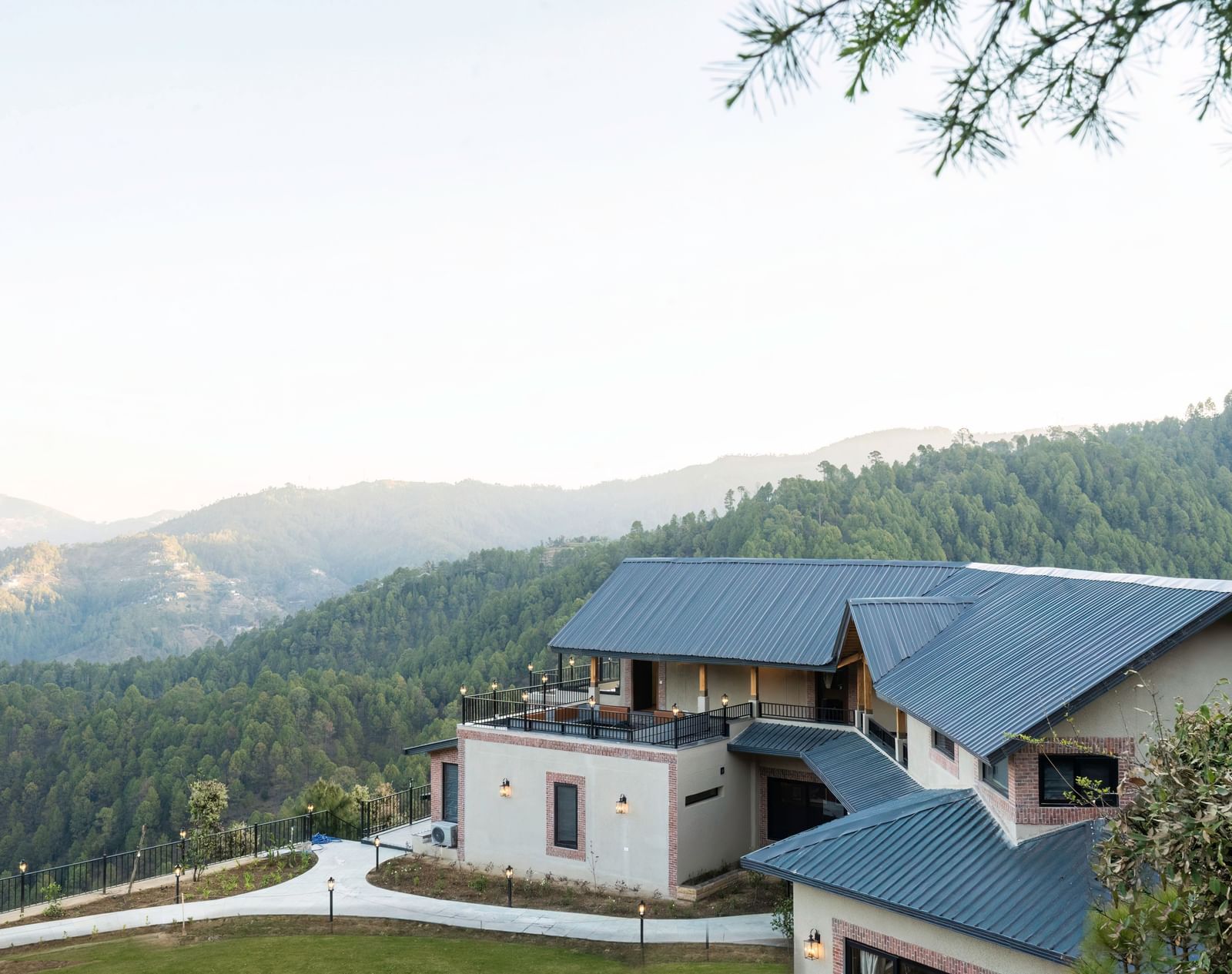 A beautiful exterior of The Chamomile Estate on a hillside with a misty mountain backdrop.