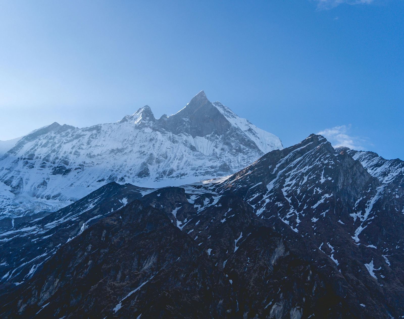 Snow-capped mountain range under a clear, bright sky.