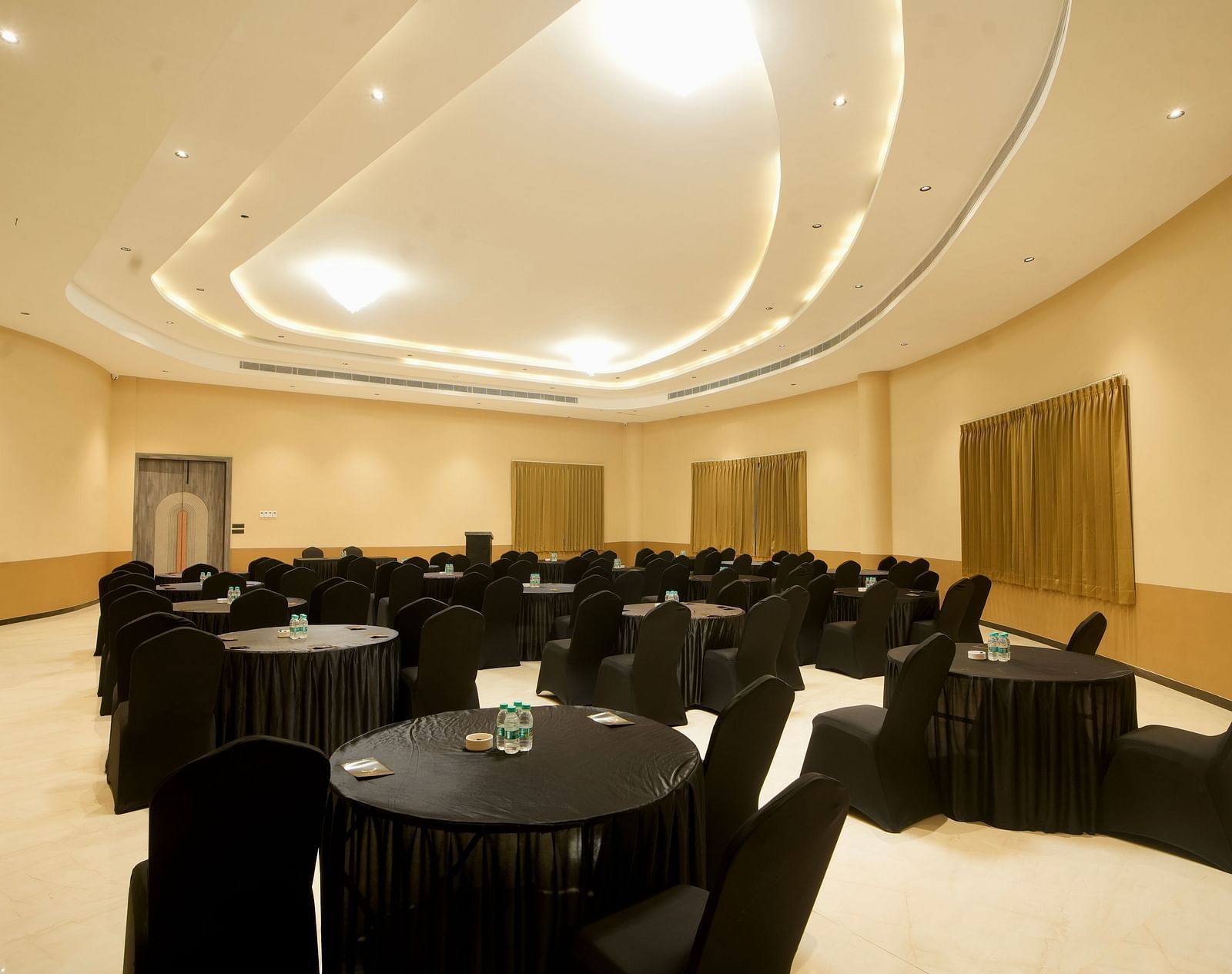 A photo of a hotel ballroom with several tables and chairs set up for an event | Conformance Hall