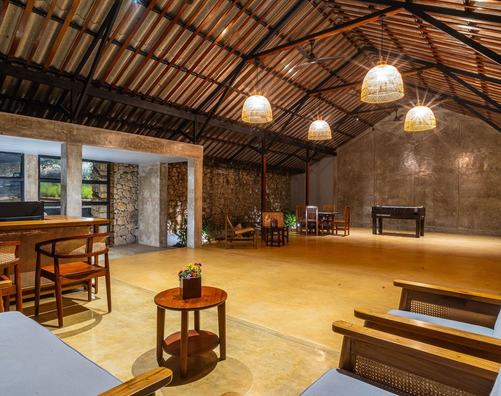  A common area at Vaastha Vagamon with exposed beams, pendant lighting, seating, and a bar counter.