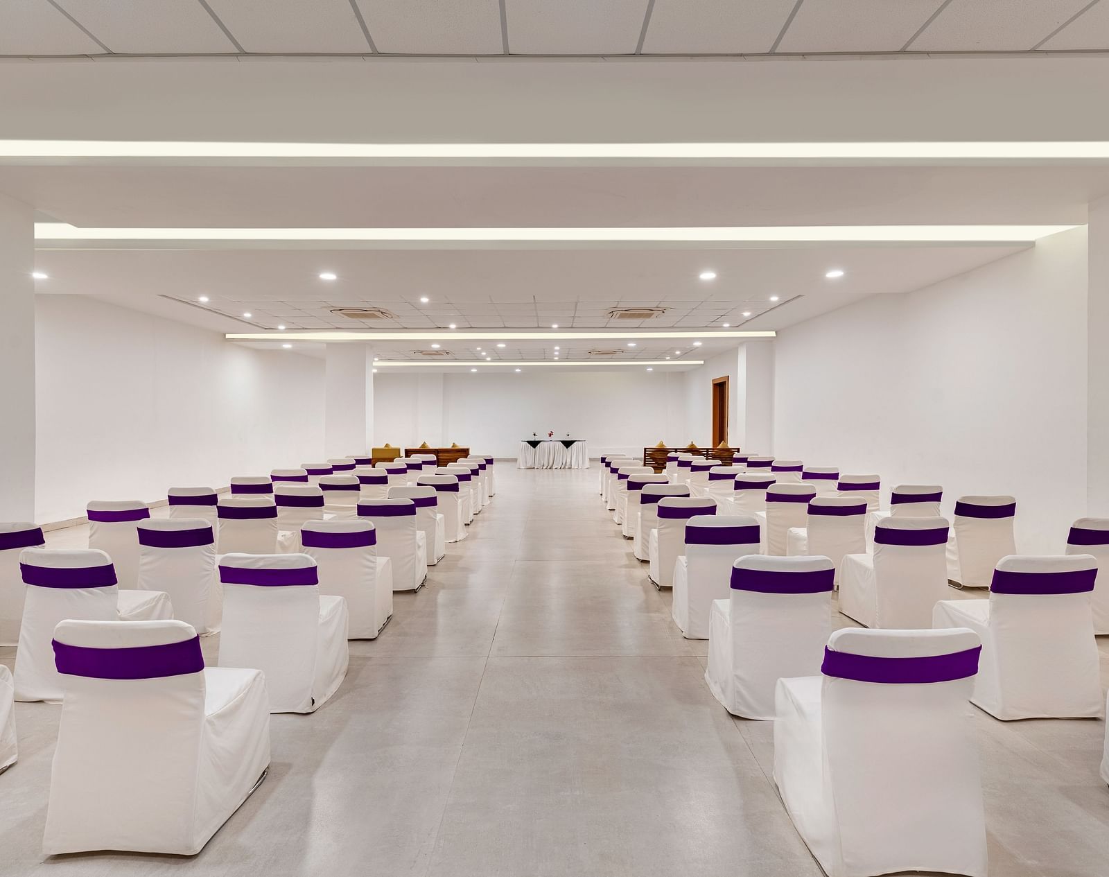 Empty conference room with rows of chairs draped with white tablecloths - Via Lakhela Resort & Spa