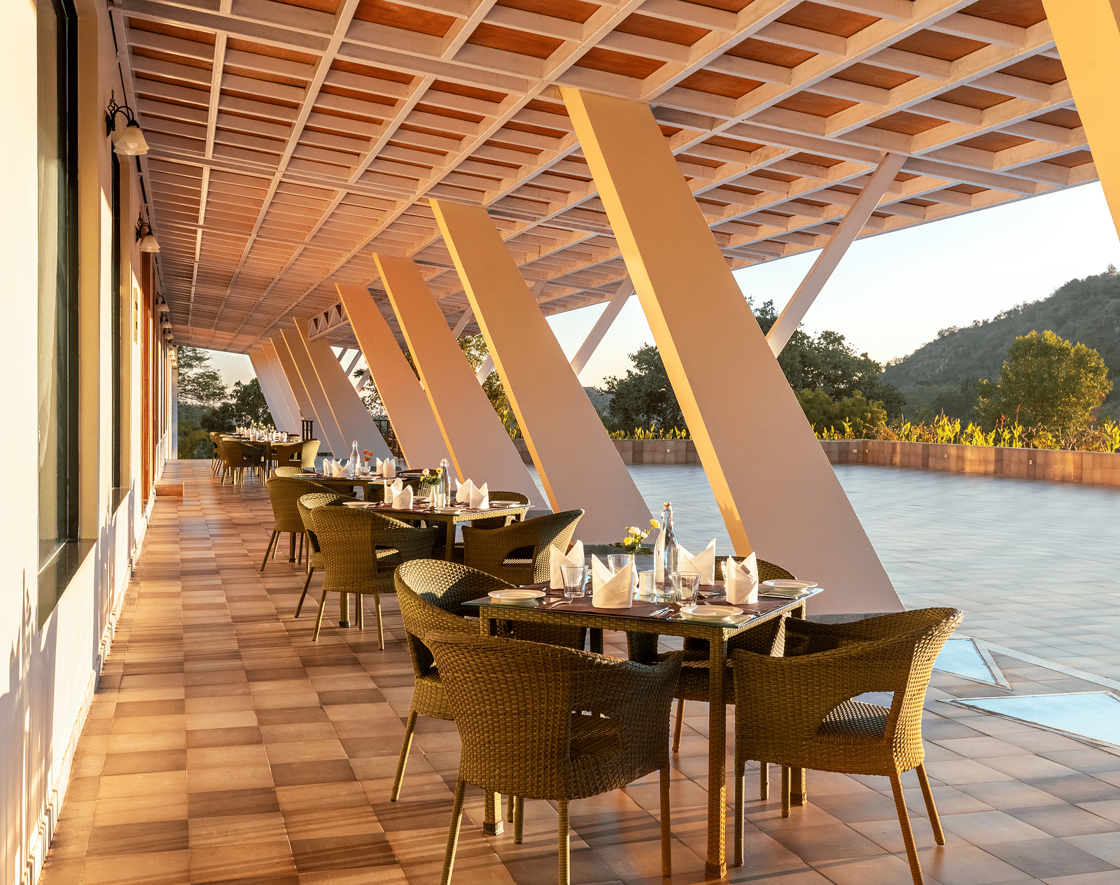 Outdoor dining area with sloped roof, tables, chairs, and a scenic view - Via Lakhela Resort & Spa