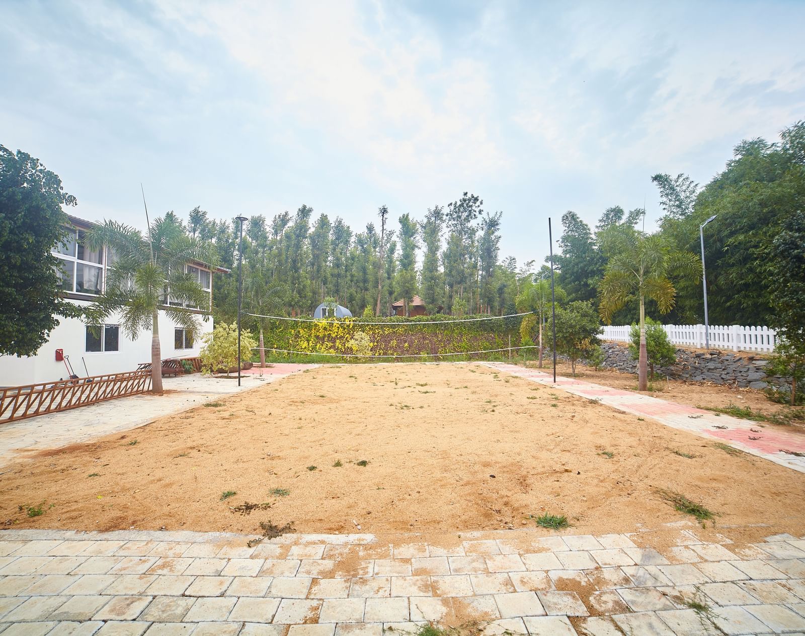 A wide, open expanse of dry, light brown ground, possibly a sports field or open space, with buildings and trees in the background under a pale sky - Vintage Trails by Ilara
