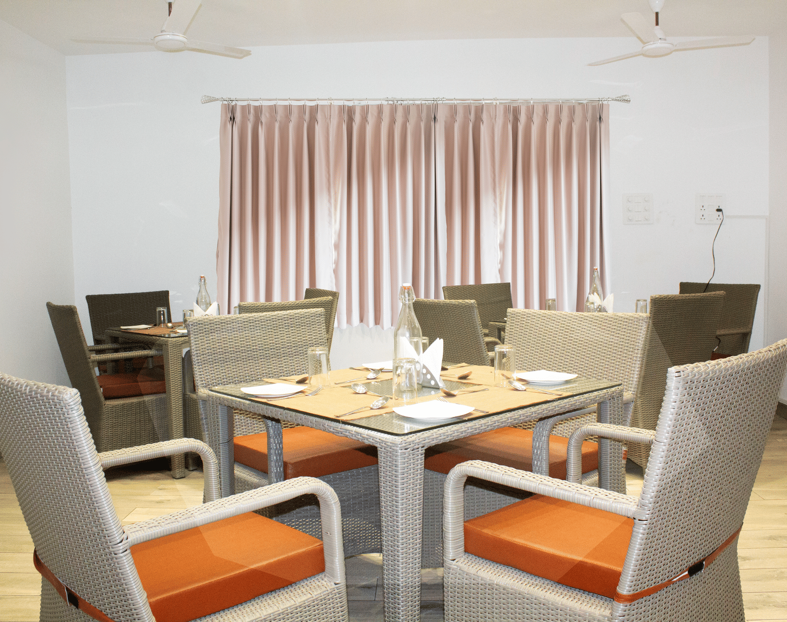 A dining table with orange-coloured cushions on the chair at the Spice and Slice Restaurant at WOW Naturefull Resorts, Yercaud.