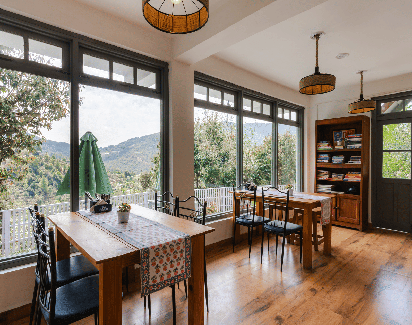 A dining area with tables and chairs next to a large window overlooking a patio at Ziran Retreat.