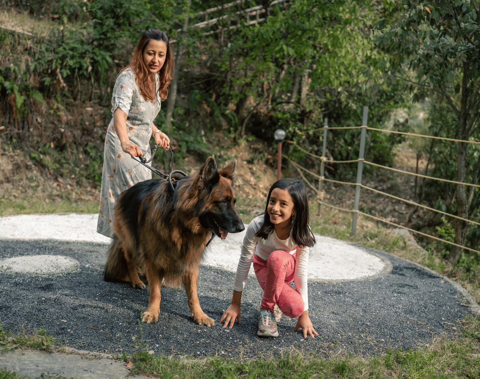 Two girls and a dog are on a path next to a fence at Ziran Retreat.
