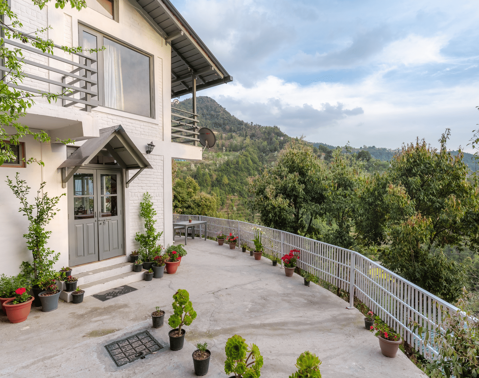An exterior shot of the Ziran Retreat building, showing the white house with a sloping road in front and a mountain view in the background.