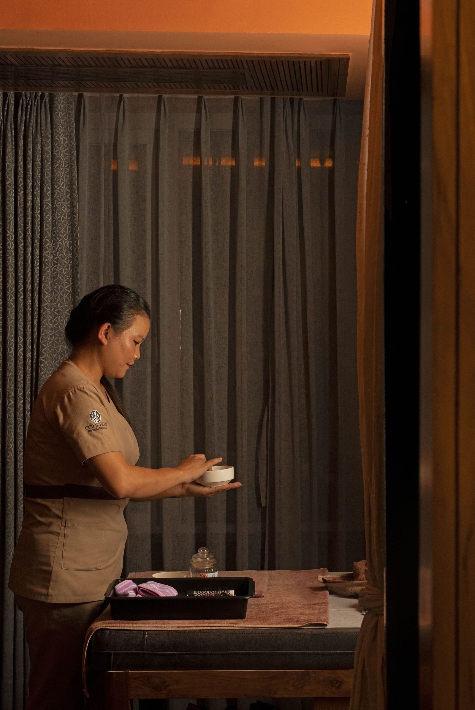 Image of Ayur Spa at Coral Reef Hotel and Spa in Port Blair featuring a masseuse preparing essentials for spa holding a little bowl