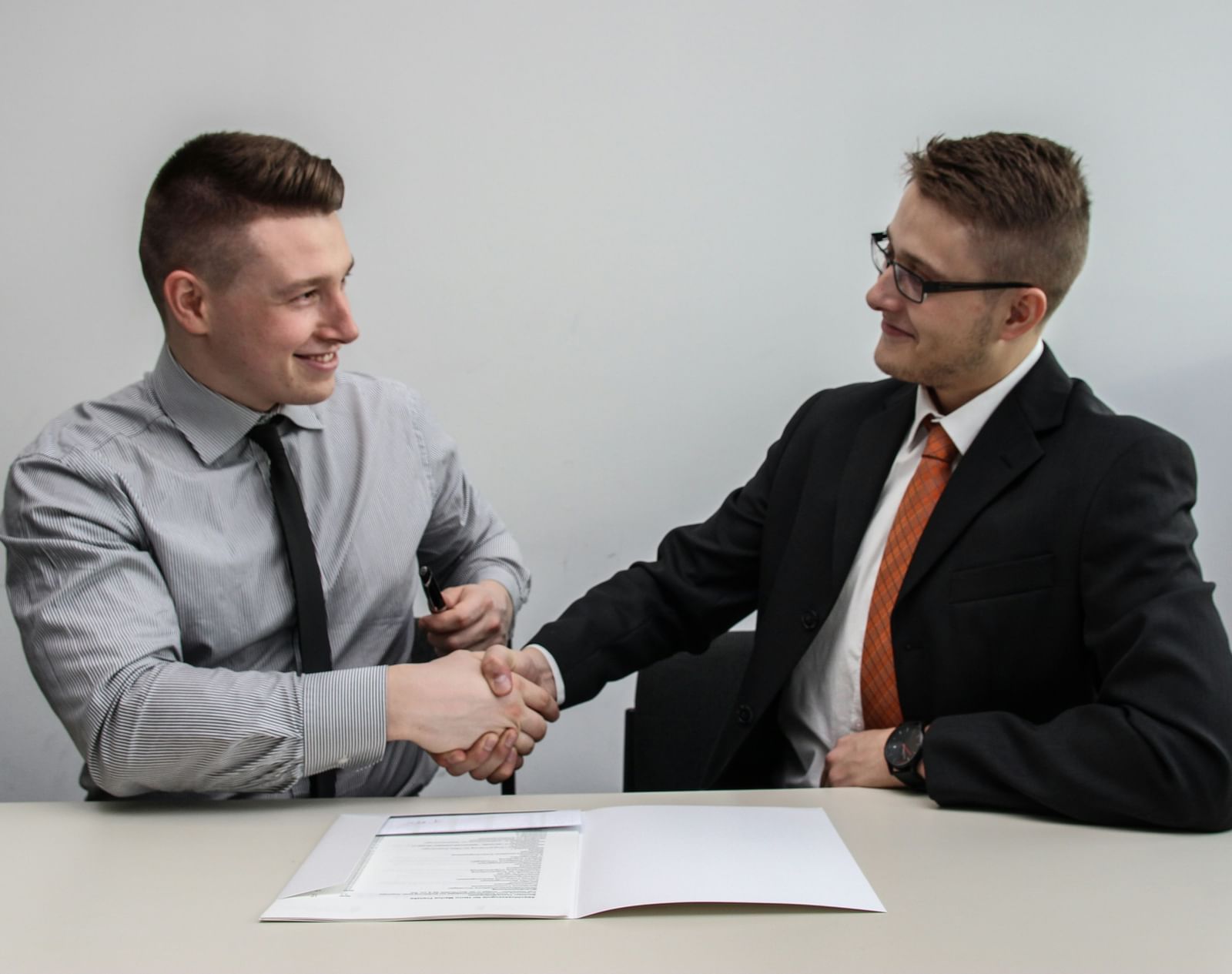 Two men in business attire shaking hands, suggesting a business agreement  | Job Placement Services