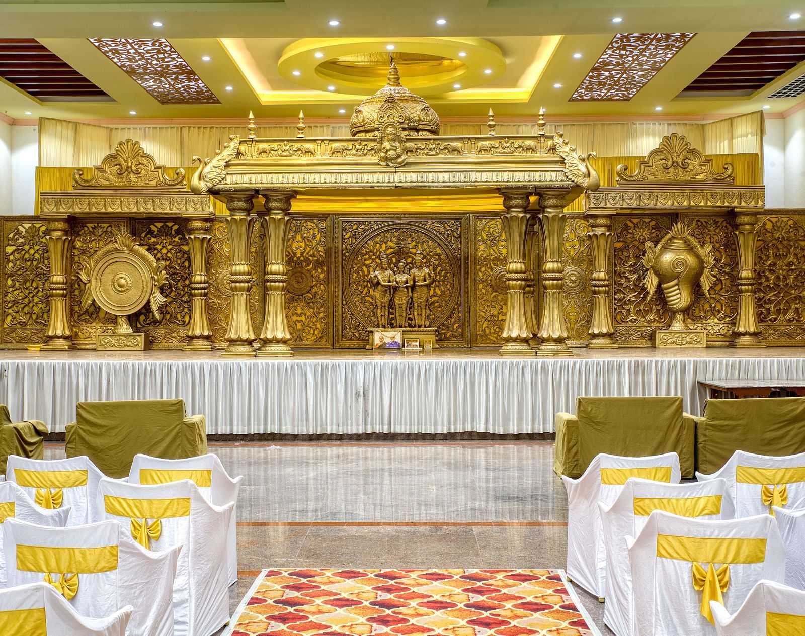 Decorated indoor wedding stage with golden backdrop and banquet seating at Kailash Conventions ECR.
