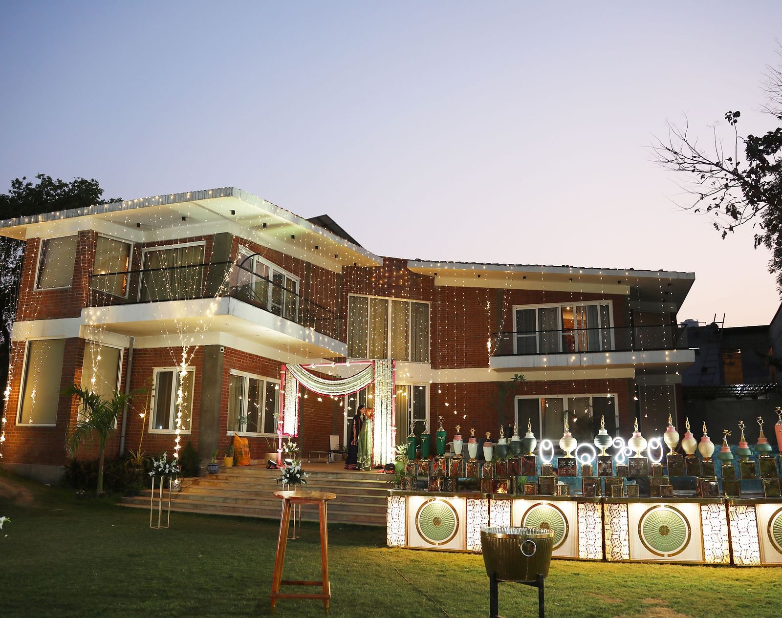 Main building of Tisya Farms, Gurgaon at dusk with lit landscaping and a clear view of the entrance area.